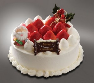 Классный новогодний торт украшенный взбитыми сливками и клубникой. НА торте сидит Санта из кулинарной мастики