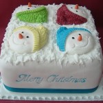 Новогодний торт украшенный снеговиками, одетыми в разноцветные вязанные шапки