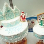 Многоярусный новогодний торт. По белой глазури - новогодний рисунок голубой пищевой краской, торт украшен Дедом Морозом из марципана
