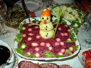 Селёдка под шубой украшена объёмным снеговиком. Три шарика из картофеля, нос - морковка, шляпка из помидора, в руке метла из зелени