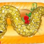 Огурцы использованы для декора салата в виде змеи, а для того, чтобы картинка была ярче добавлены помидорки